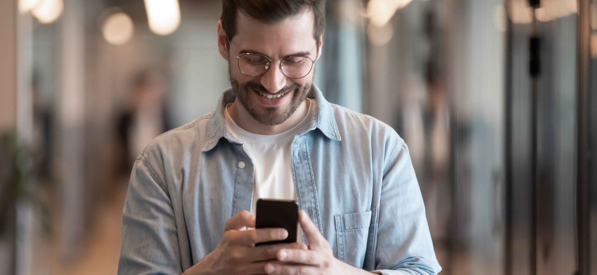 smiling-male-employee-using-modern-smartphone-texting